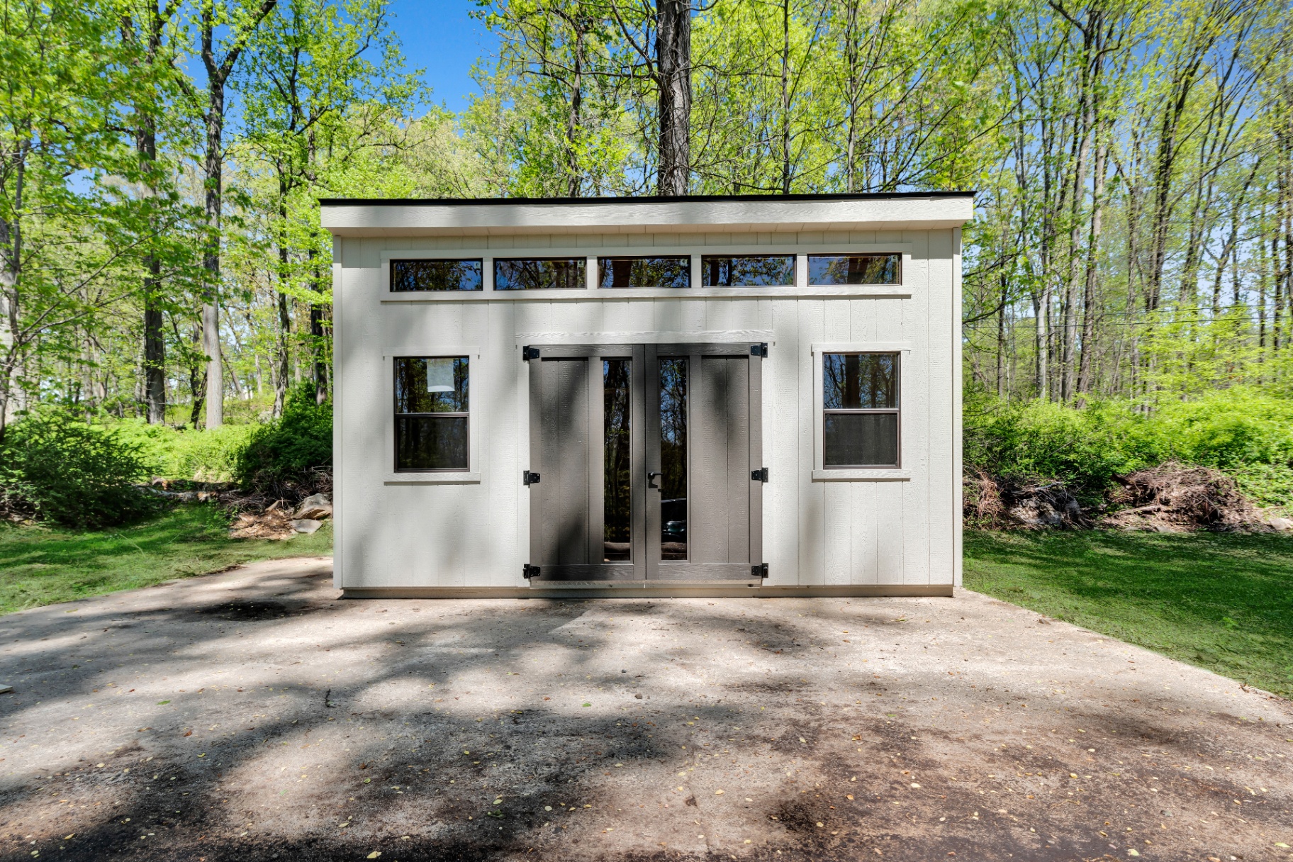 White modern studio shed at the edge of the woods