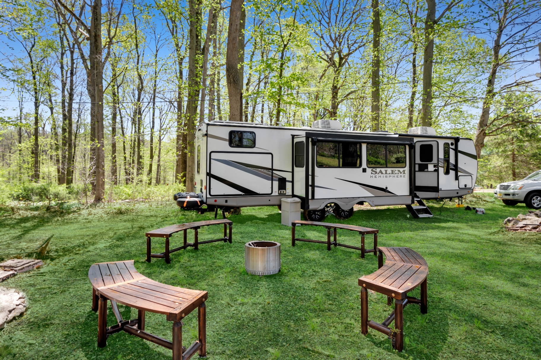 Fire pit ringed with curved wooden benches beside the RV